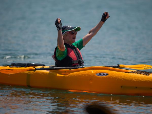 Athlete with arms raised in celebration whilst sitting in kayak