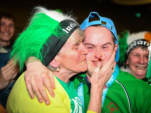 Mother kissing Special Olympics athlete on cheek