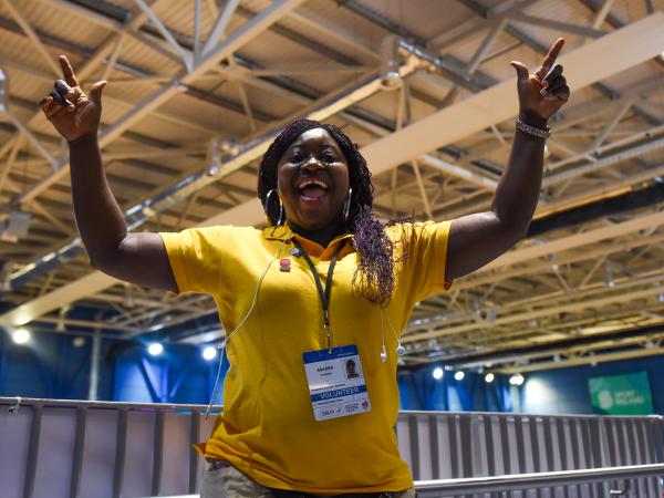 Smiling and happy volunteer lady with arms in air