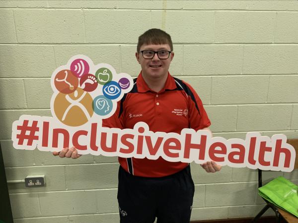 athlete holds inclusive health sign
