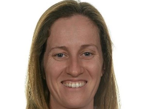 Woman with long brown hair and white shirt smiles at camera