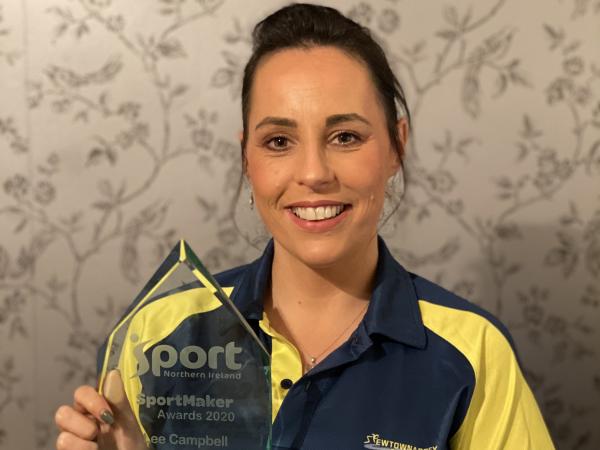 Woman holds trophy and smiles at camera