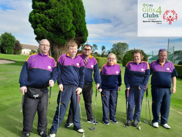 Group of athletes stand on golf course posing for photograph