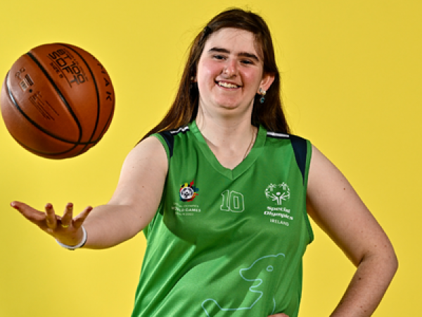 Girl smiles at camera and throws basketball