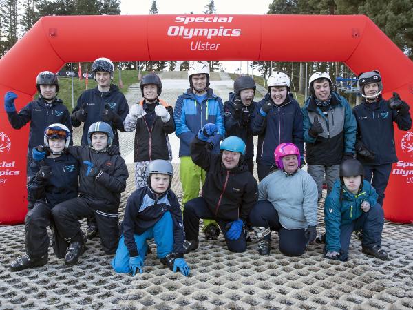 Team of skiers stand under arch and smile at camera