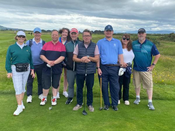 This image shows people at Connaught at the Portmarnock Golf Event 2025 smiling for a photo some having golf clubs in their hands.