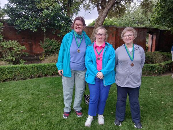 This image shows three people smiling for a photo at Portmarnock Golf Event with medals around their necks.