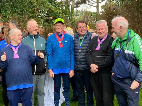 This image shows people smiling for a photo at Medals at the Portmarnock Golf Event with medals around their necks.
