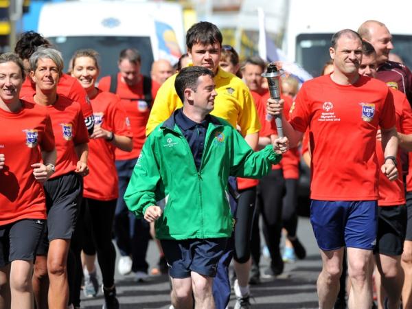 This image shows people running for the Special Olympics holding a torch together.