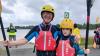 This image shows two people with arms around each other with paddles for kayaking smiling for a photo.