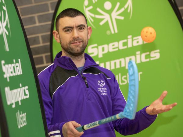 Man wearing Team Ulster kit holds stick and ball to camera