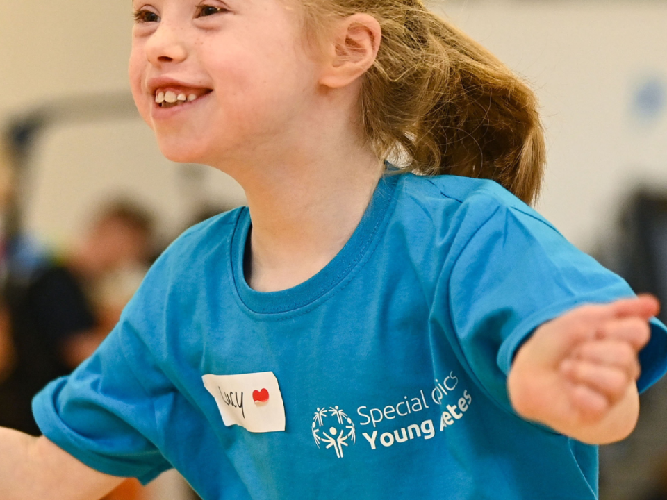 This image shows a young Athlete smiling and holding her arms out.