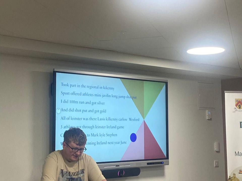 This image shows an athlete delivering a presentation about taking part in a regional athletics event