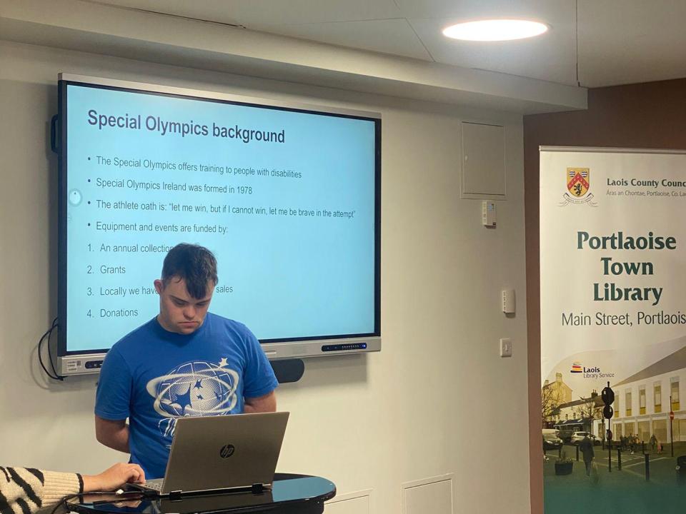 This image shows an athlete delivering a presentation about the Special Olympics athlete oath and its background