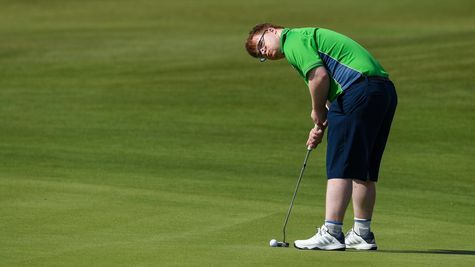 Special Olympics athlete holding golf club and putting on the green.