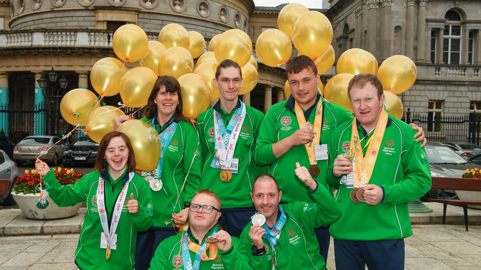 Special Olympics athletes wearing medals and holding balloons