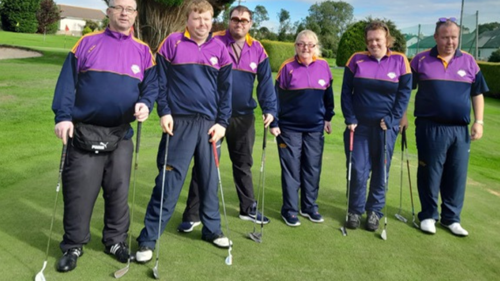 Group of athletes stand on golf course posing for photograph