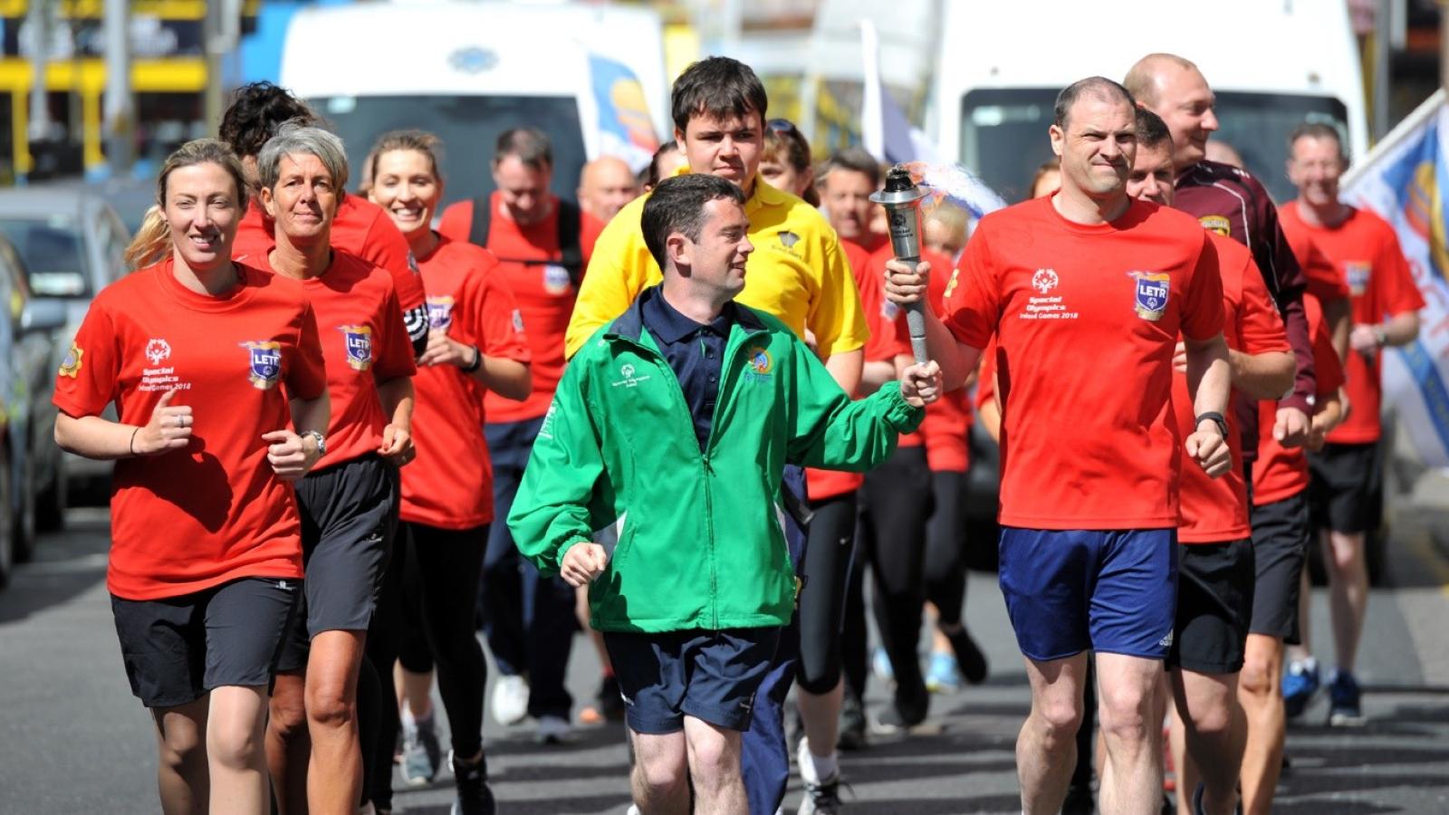 This image shows people running for the Special Olympics holding a torch together.